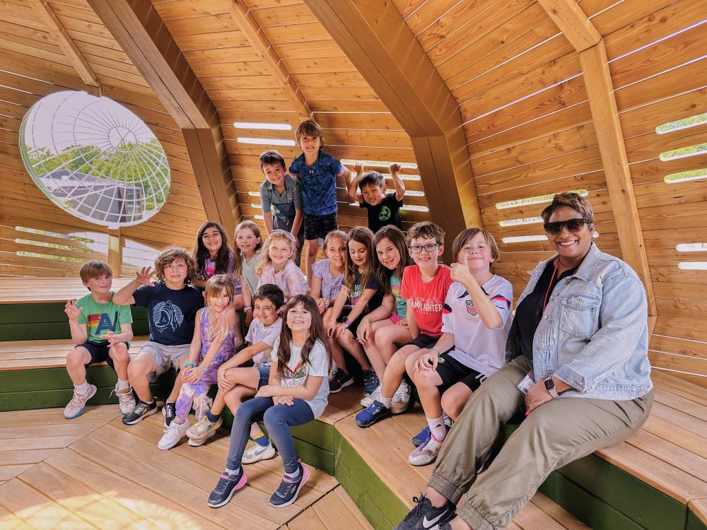 Teacher and a school class in huge wooden tree structure