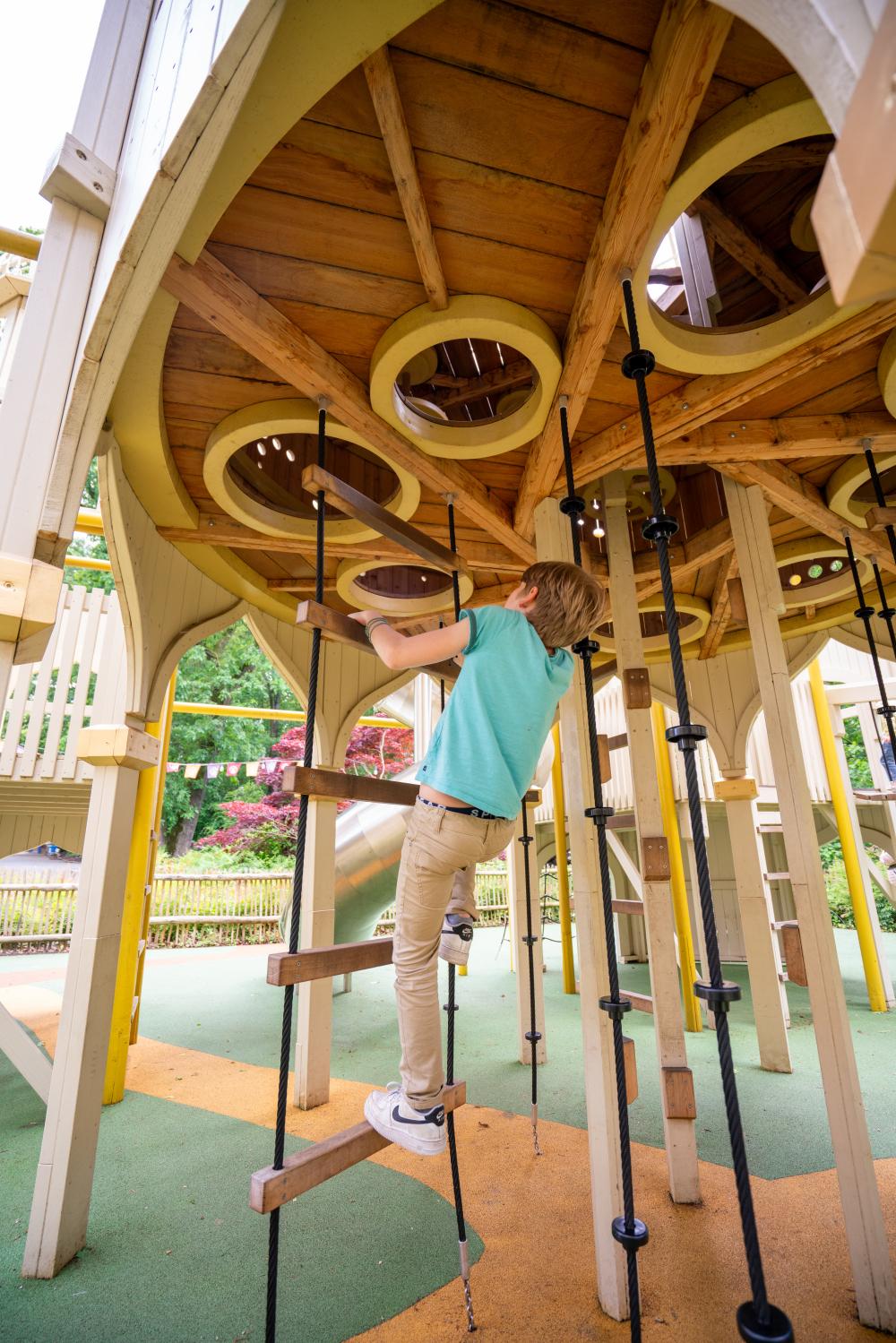 Boy climbing up playground structure on rope ladder