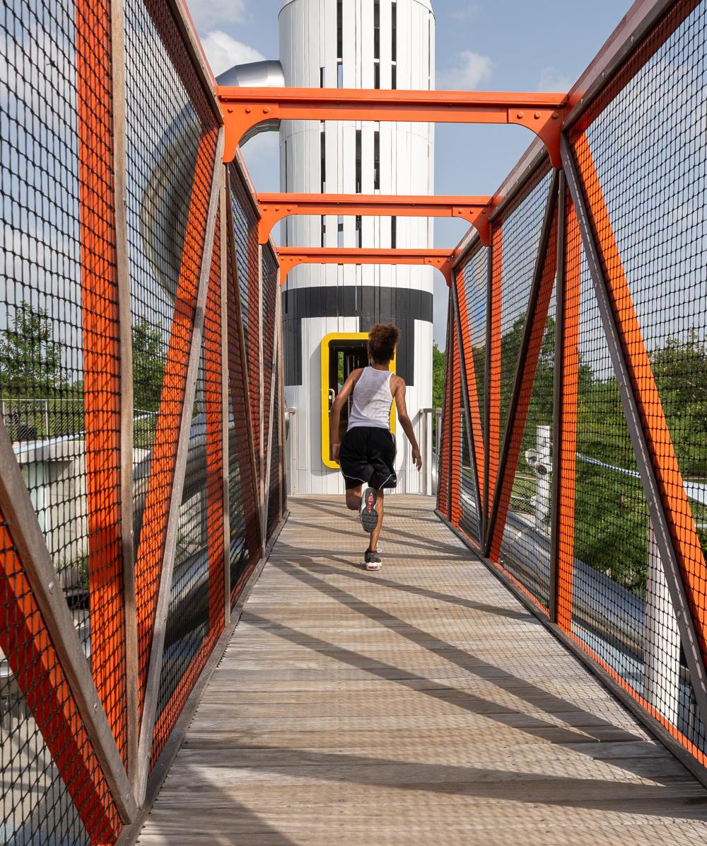 Boy running down wooden bridge to playground rocket