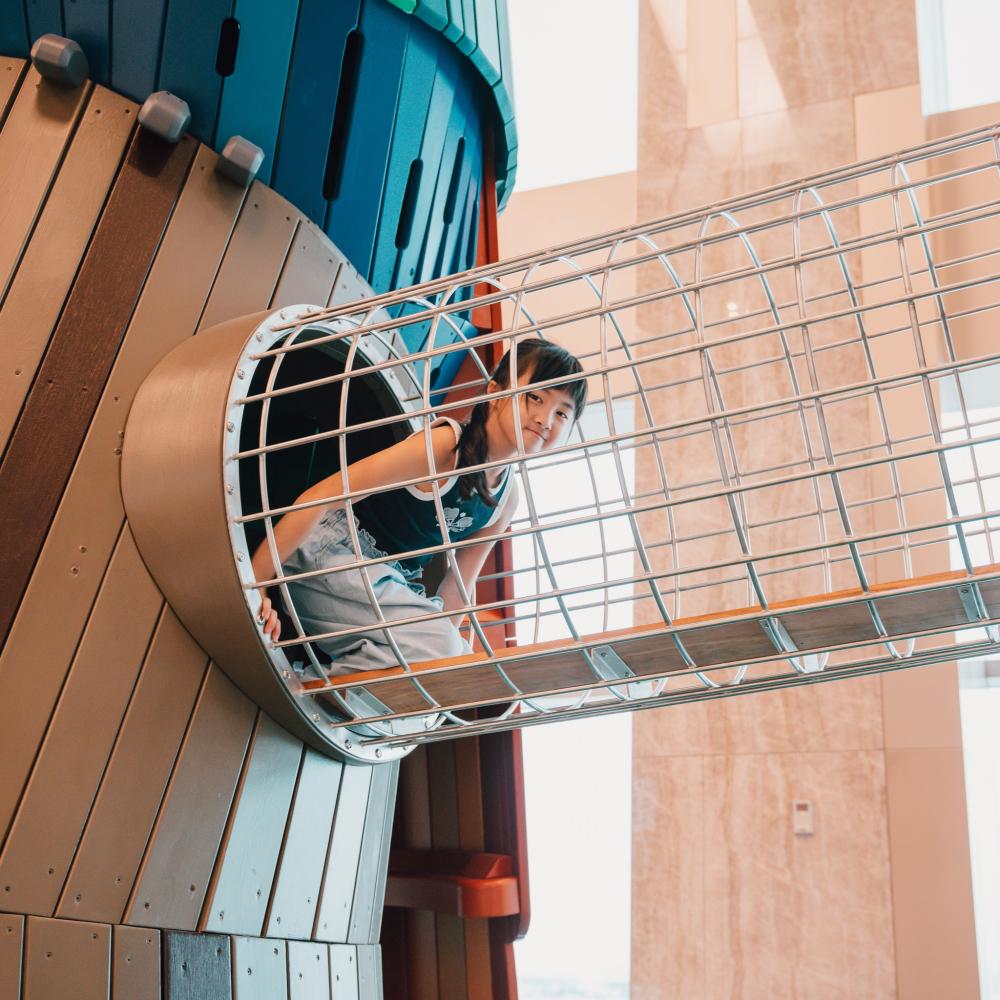 Girl climbing through playground tunnel