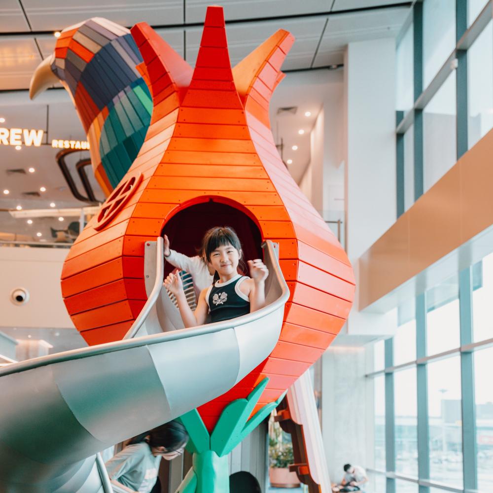 Girl sliding down playground slide at Changi Airport