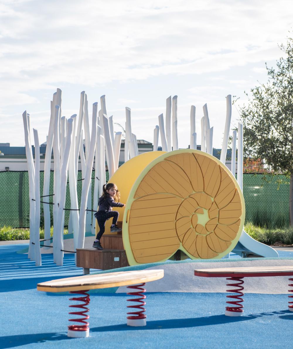 Girl climbing fun snail shaped slide at whale playround
