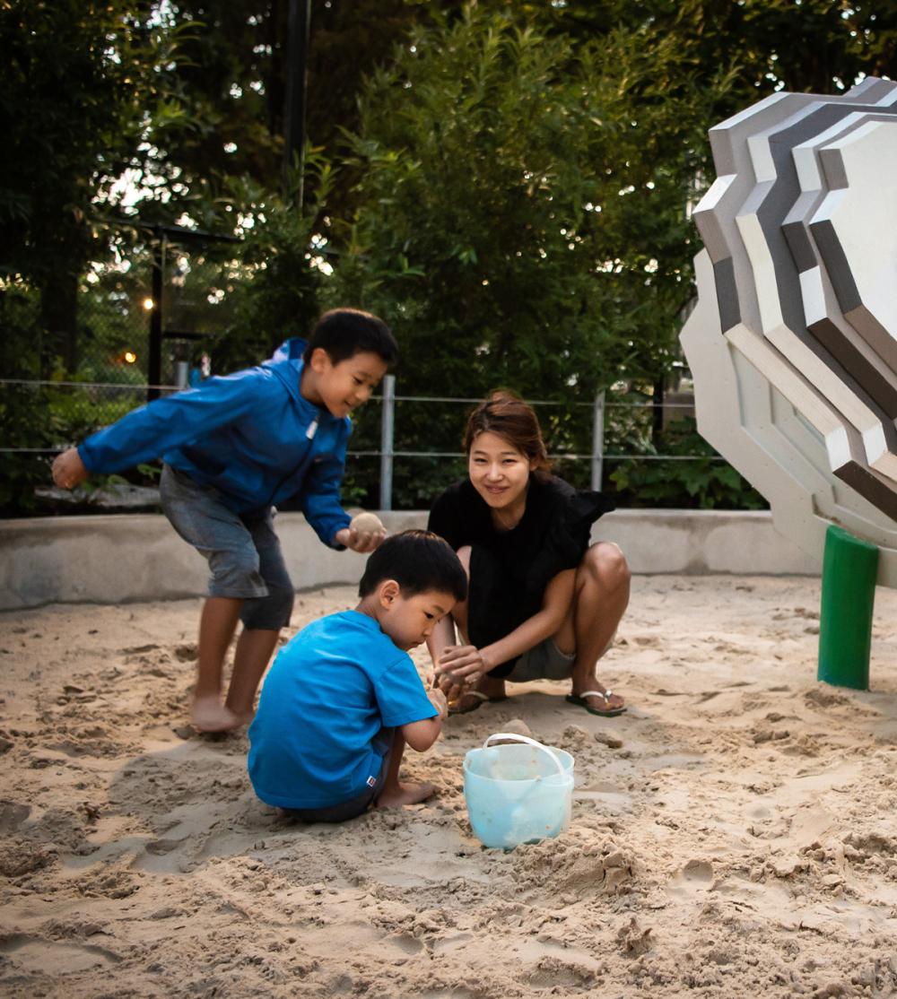 Kids and lady playing in sand at playground