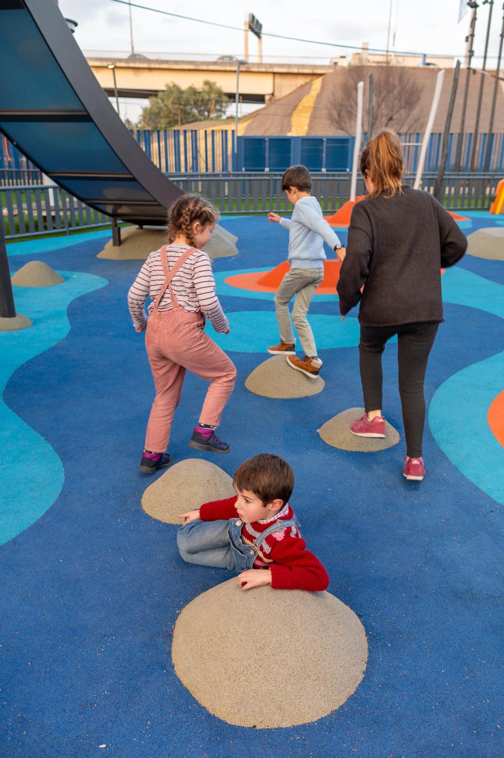 Children jumping on rubber mounds in impact flooring of playground