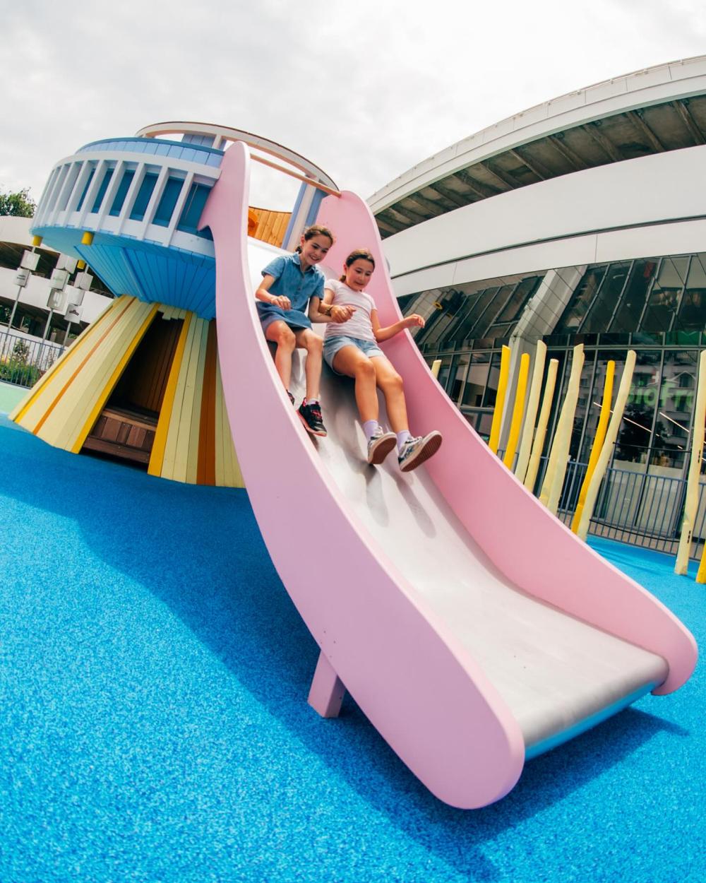 Girls sliding down from UFO playground
