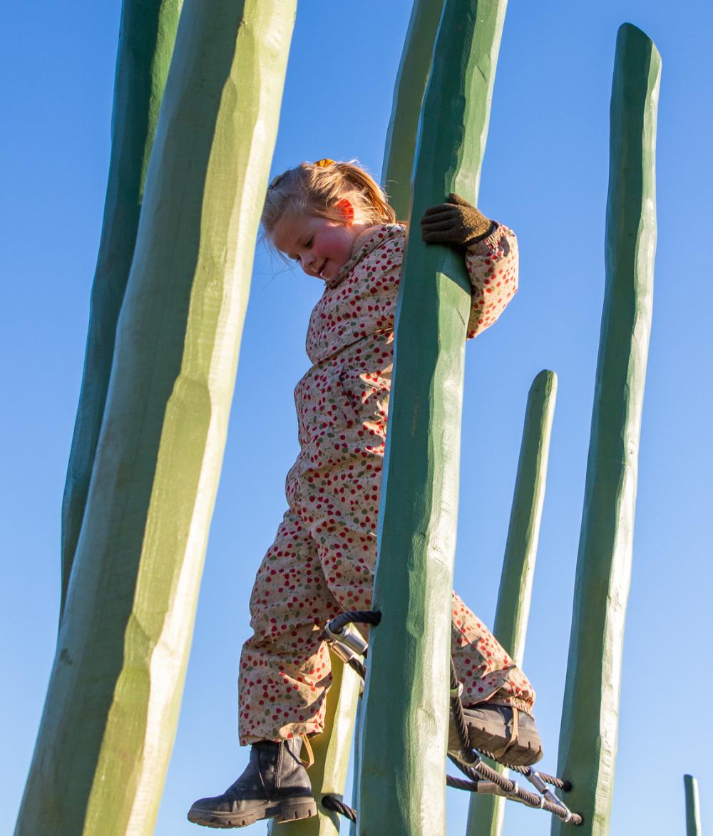 Girl climbing on wooden posts at MONSTRUM playground