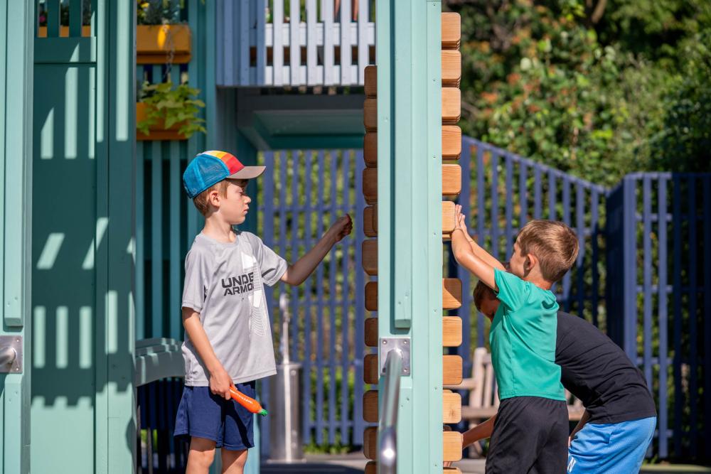 Boys playing together on each their side of puzzle wall at playground