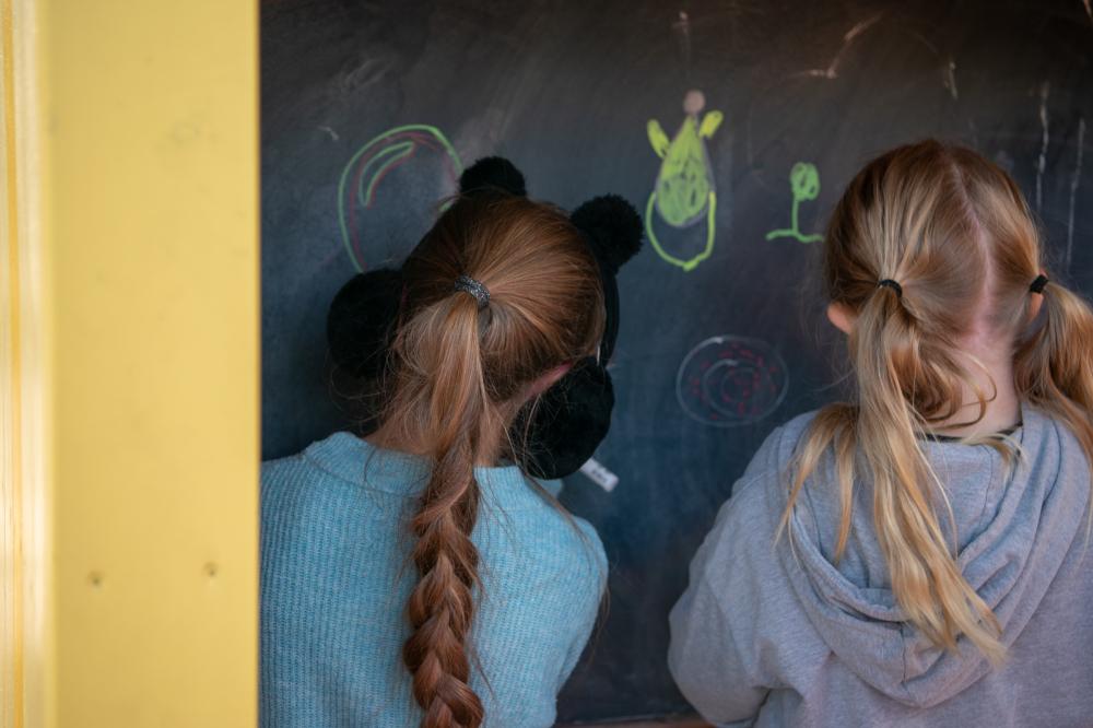 Girls inside play house drawing with chalk