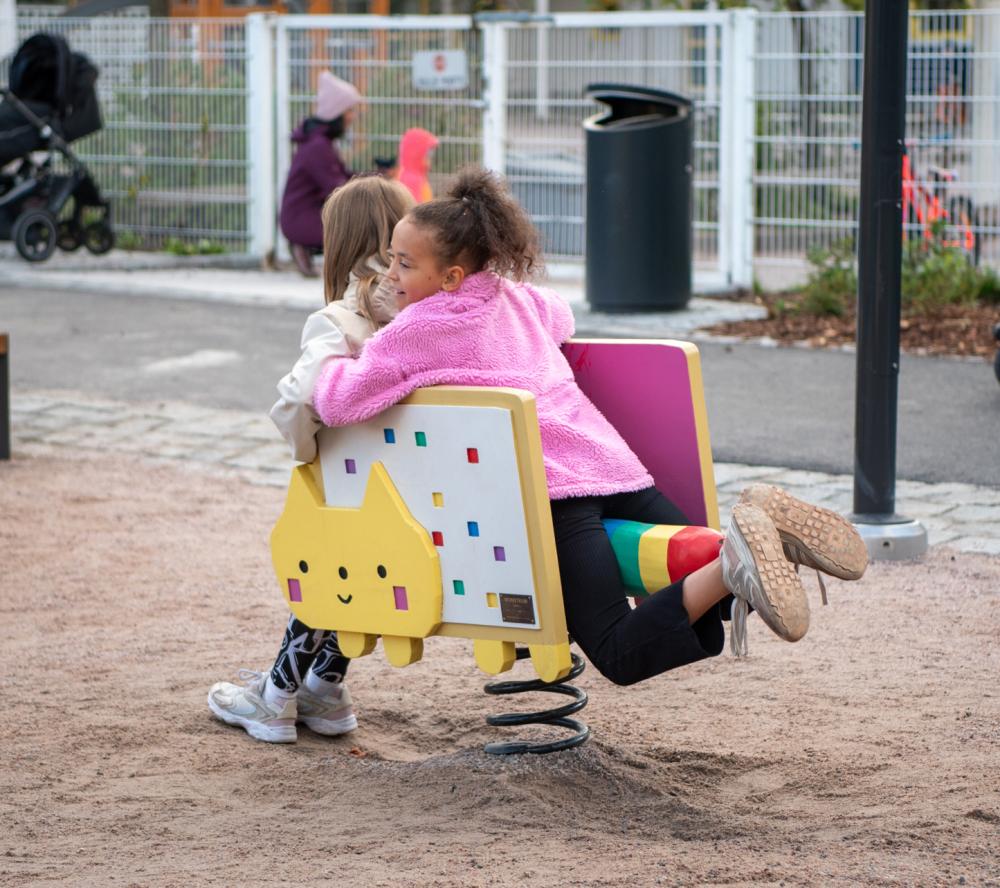 Two kids playing on Nyan cat themed spring rocker