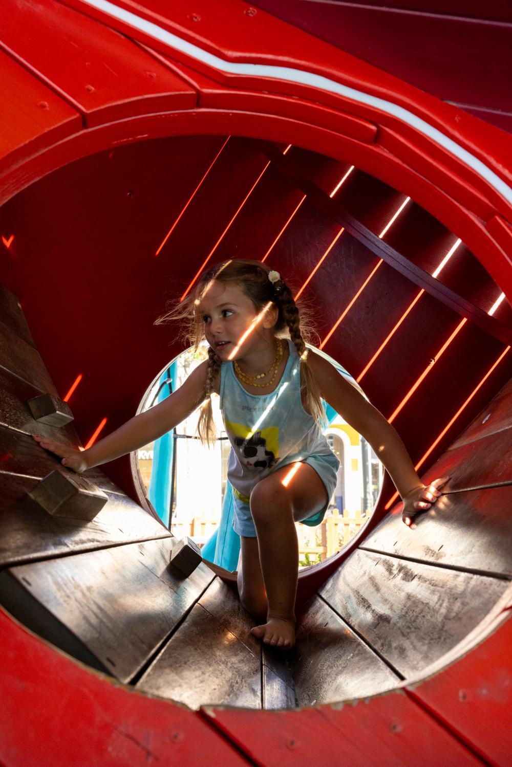 Girl climbing into big wooden butterfly play structure