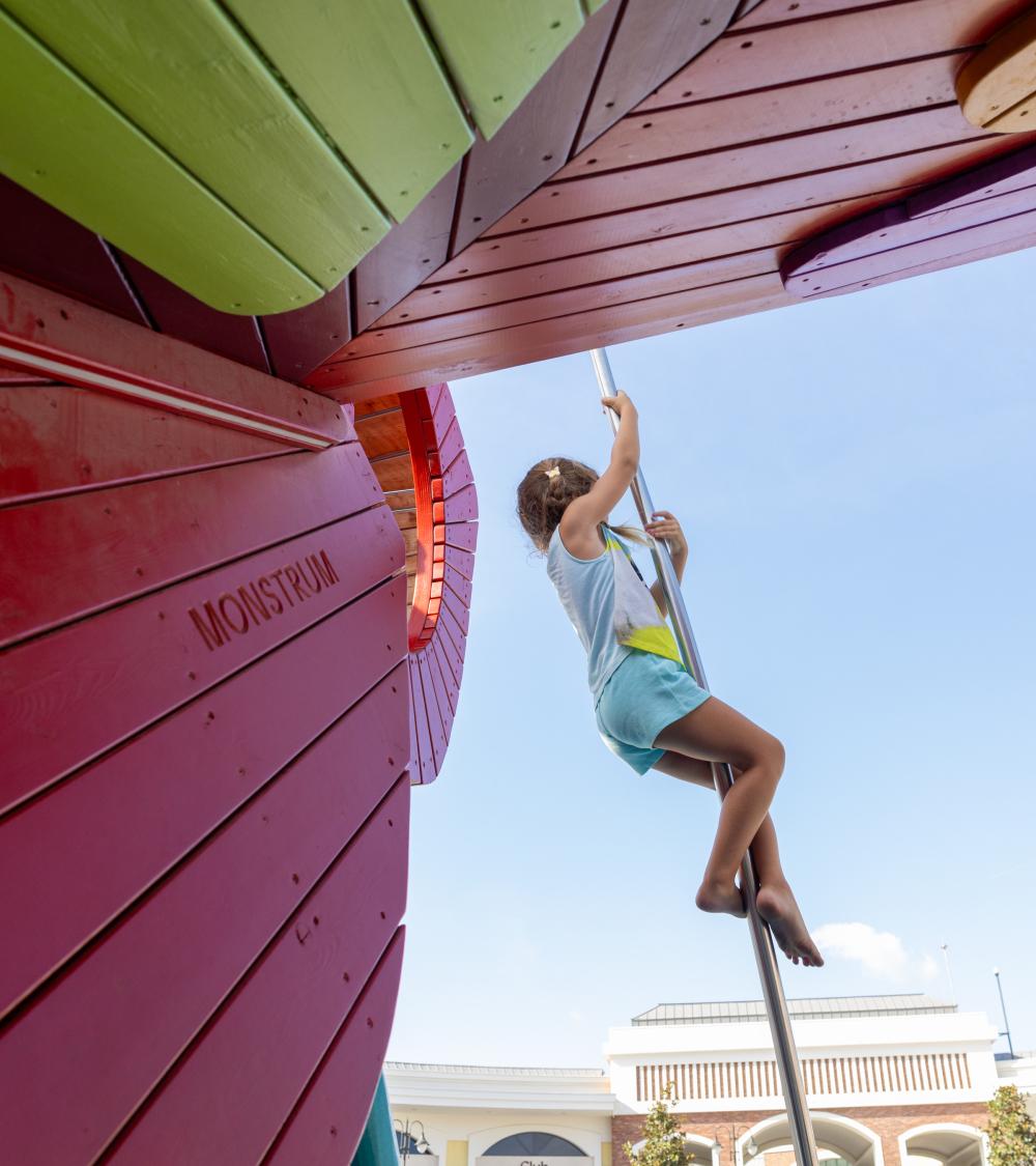 Girl sliding down steel pole at creative playground