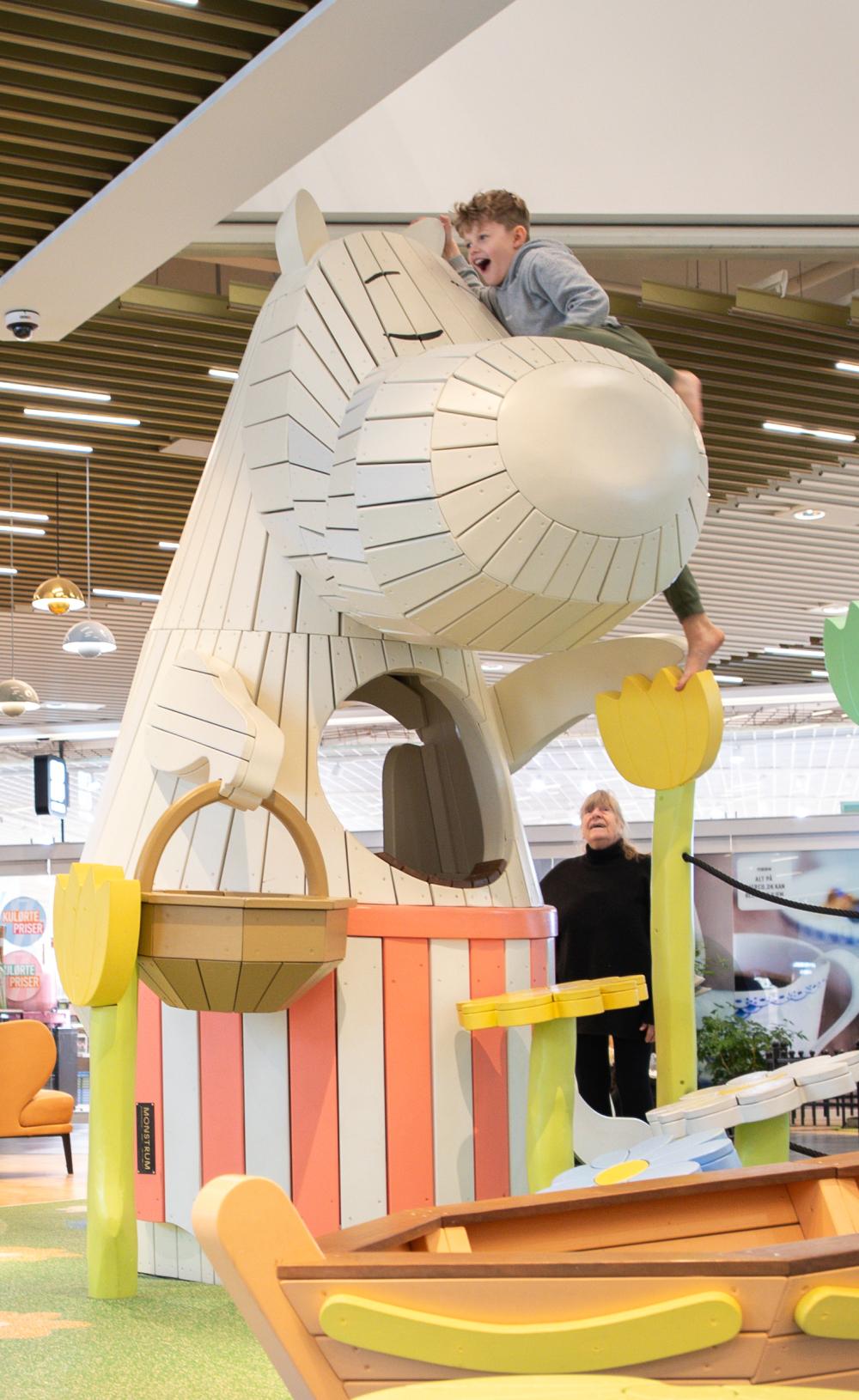 Boy climbing high up on Moomin play sculpture