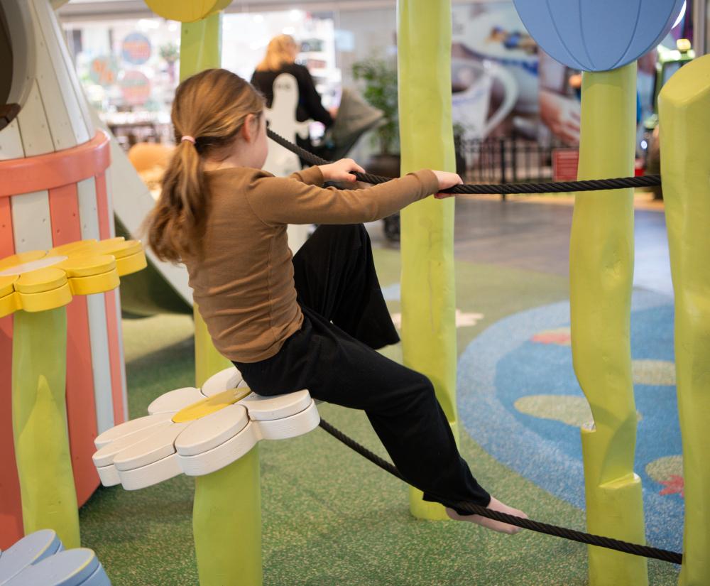 Girl climbing on ropes on obstacle course at playground
