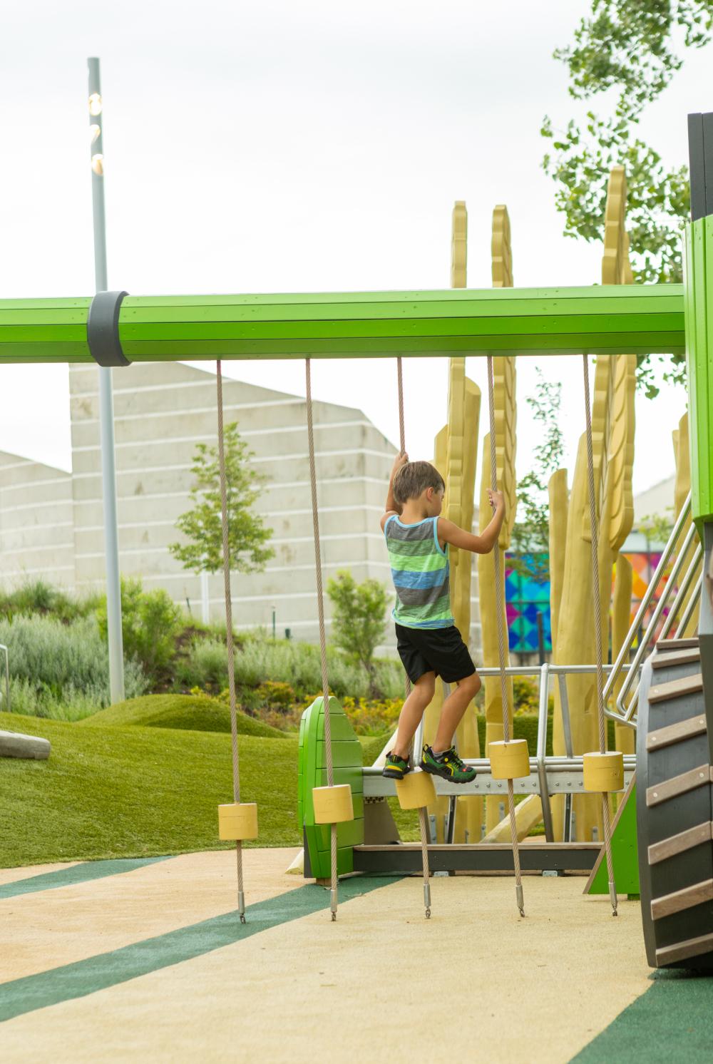 Boy climbing on rope climber at themed playground