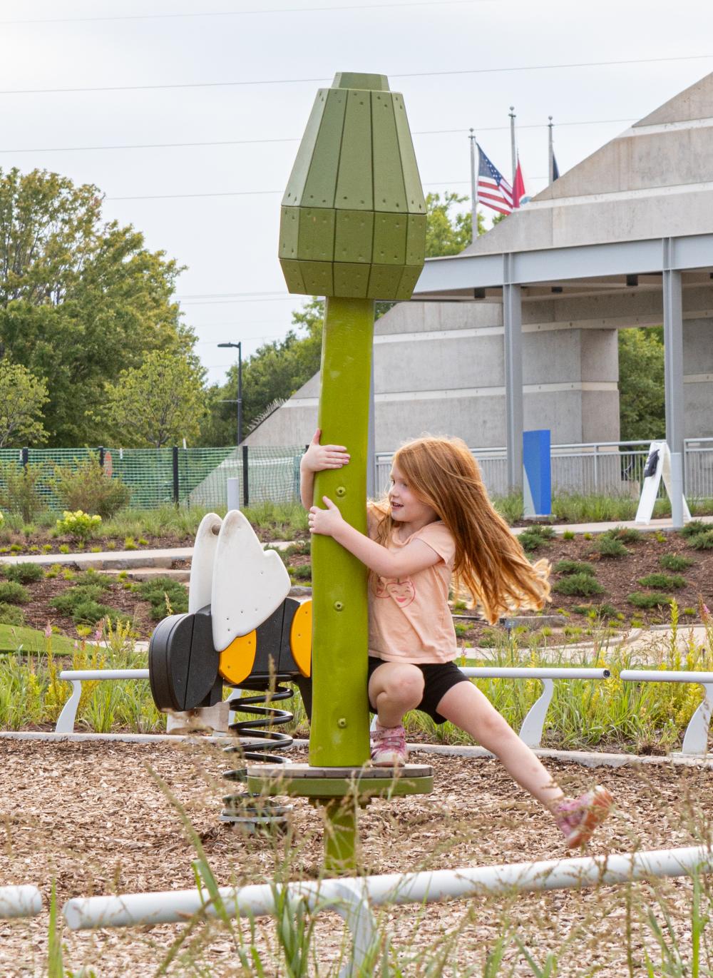 Girl spinning on carousel at sunflower themed play area
