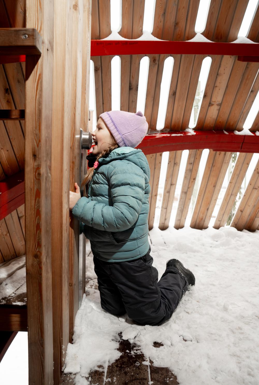 Girl using talking tube playground feature