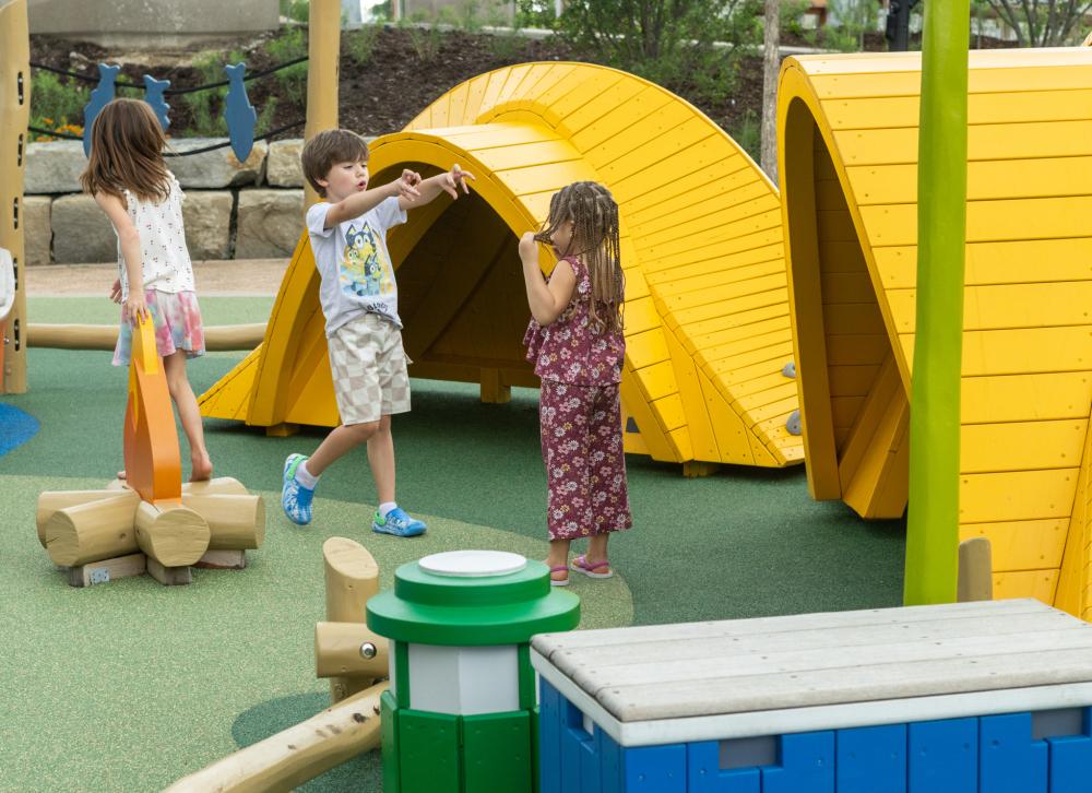 kids playing and laughing in front of wooden playground tents